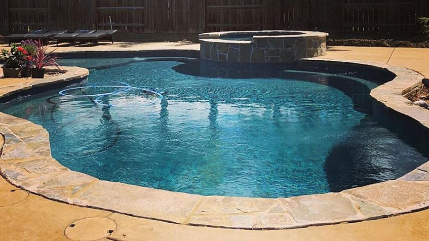 A medium-sized backyard pool with a raised spa and stone coping in a private yard.